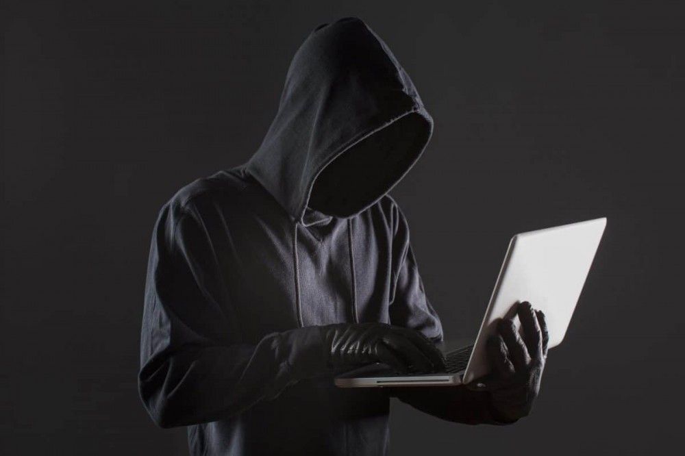 拿着笔记本电脑的匿名黑客的图像