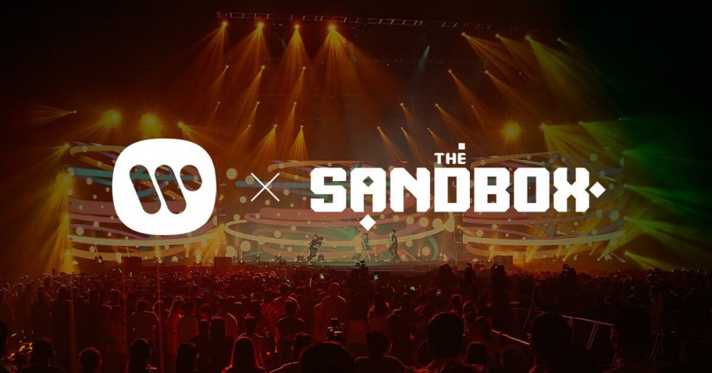 舞台前有一群虚拟人，支持 The Sandbox 的 Warner Music Game Jam。