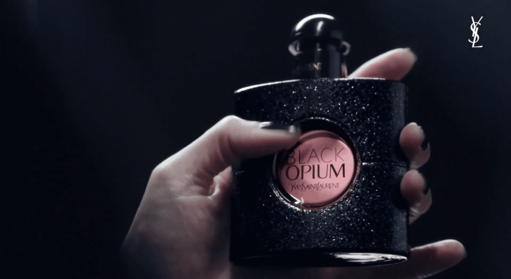 一个拿着 Yves Saint Laurent“Black Opium”香水的人，最新的 NFT 活动即将启动。